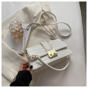 Close-up of white crocodile pattern shoulder bag with gold metal buckle and chain strap