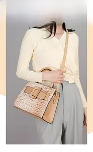 Detail view of crocodile-embossed leather tote with signature square buckle and top handle
