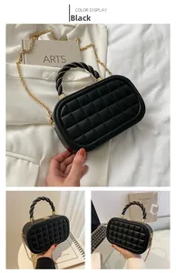Detail view of black quilted box bag with woven handle and gold chain strap