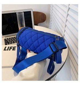 Detail of blue quilted nylon cylinder bag with wide strap and quilted rhombus pattern