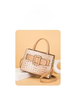Detail of beige faux crocodile leather handbag with metal buckle and shoulder strap
