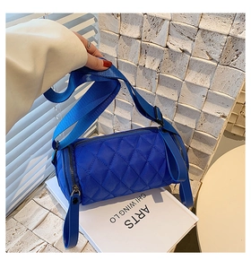 Macro detail of dark blue quilted nylon barrel crossbody bag with wide fabric strap