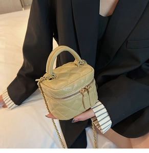 Close-up of beige quilted crossbody bag with gold chain strap and top handle