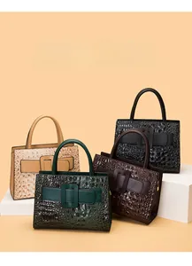 Detail of four crocodile pattern bags in beige, green, brown, and black on display