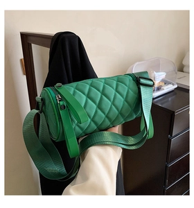 Detail of emerald green quilted cylinder bag featuring smooth nylon finish and wide strap