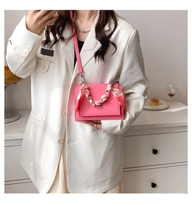 Detail of pink leather crossbody bag featuring a floral scarf wrapped chain strap