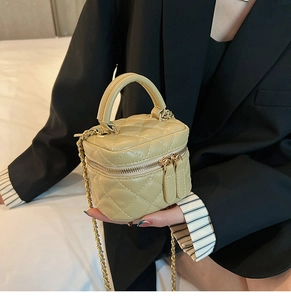 Macro detail of beige quilted micro bag with gold chain strap and top handle on a model