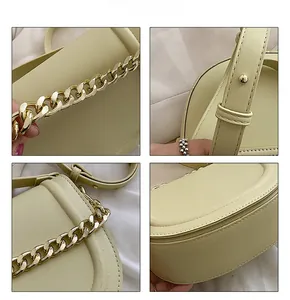 Close-up of premium cream saddle bag featuring chunky gold chain and fine stitching