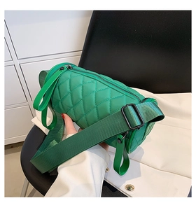 Detail of emerald green quilted cylinder bag with wide woven strap and diamond stitching