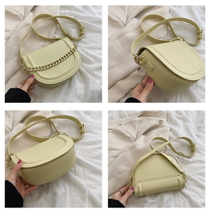 Detail view of a pale yellow saddle bag with chunky gold chain and smooth leather finish