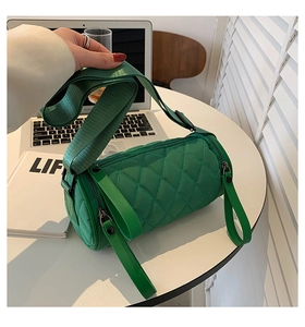 Detailed close-up of neon green quilted cylinder bag with wide strap and zipper detail