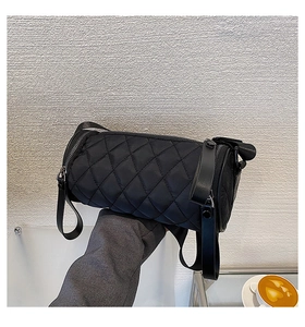 Detail of black quilted nylon cylinder bag with adjustable strap in a lifestyle setting