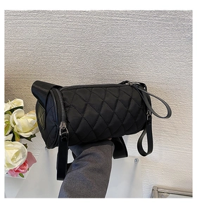 Detail of black quilted cylinder bag with leather handles and diamond stitch nylon fabric