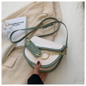 Detail of saddle bag featuring green trim, crocodile embossed flap and gold metal ring