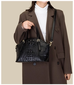 Detail of black crocodile texture handbag with gold hardware and shell shape silhouette