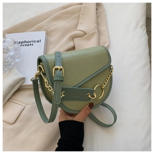Detail view of green crocodile pattern saddle bag with gold chain and leather strap
