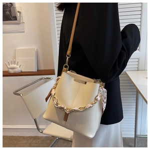 Detail of cream bucket bag featuring a gold chain entwined with a floral silk scarf