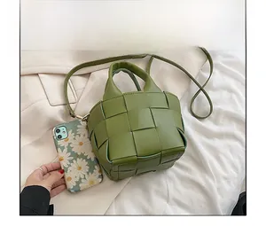 Mini green woven handbag size comparison with a phone for scale, showing compact design