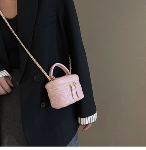 Close-up of pink quilted mini vanity bag with gold chain strap on a model