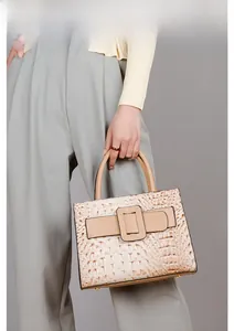 Detail of beige crocodile embossed handbag with signature wide strap and square buckle