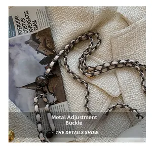 Detailed close-up of golden spherical buckle on white leather and metal chain strap