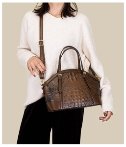 Detail of dark brown crocodile embossed shell bag with gold hardware on model