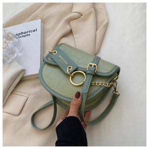 Detail of avocado green saddle bag with crocodile texture and golden hardware accents