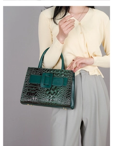 Macro shot of dark green crocodile texture bag with square buckle and gold protective studs