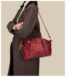 Detail of red crocodile pattern Boston bag on shoulder with wool coat and leather strap