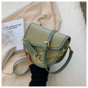 Detail of light green saddle bag showing crocodile skin texture and metal chain strap