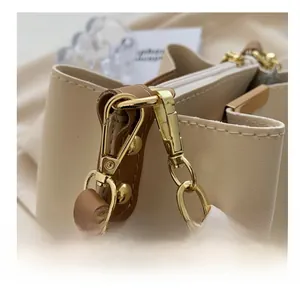 Close-up of golden hardware hook on leather bucket bag with decorative printed silk scarf