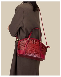 Macro shot of dark red crocodile embossed leather handbag with gold metal hardware details