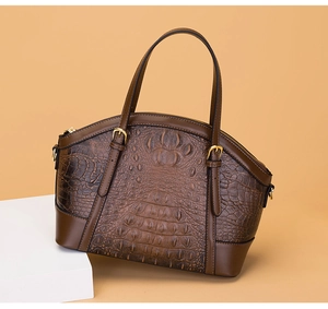 Detail of brown crocodile embossed leather handbag with golden zipper and sturdy handle