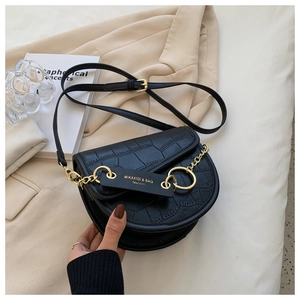 Detailed shot of black crocodile pattern saddle bag with golden chain and branding tag
