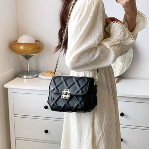 Elegante schwarze Stepptasche mit Goldkette und Juwelenschnalle in Wohnambiente