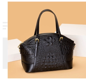 Detail of black crocodile texture handbag with gold hardware on minimalist display