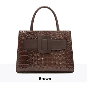 Detail of brown crocodile pattern handbag with large square buckle and double handles