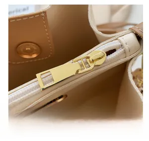 Detailed macro view of the smooth gold metal zipper and magnetic closure of the bucket bag