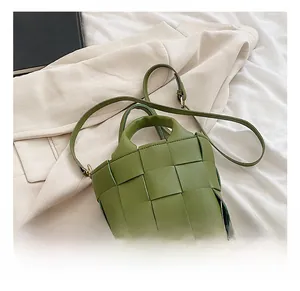 Detail view of grass green woven handbag with signature large checkered pattern and strap