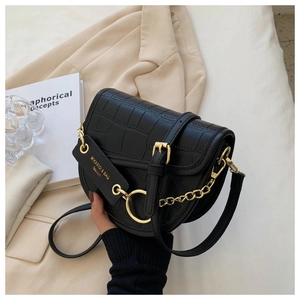 Detailed close-up of black crocodile embossed saddle bag with gold ring and chain link