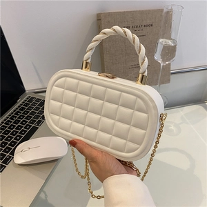 White quilted box bag with gold chain strap and woven top handle shown in lifestyle setting