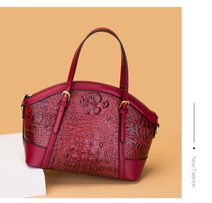 Detail of burgundy crocodile pattern handbag showing rich leather texture and golden buckles