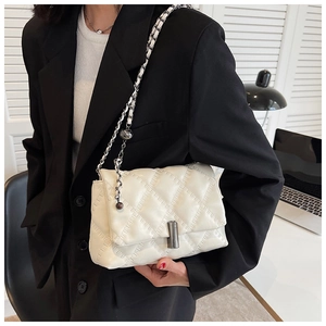 Close-up of white quilted crossbody bag with a metal cylinder lock on a black blazer