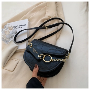 Detail shot of black crocodile embossed saddle bag with elegant gold chain and strap