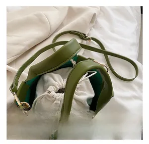 Detail view of olive green woven handbag featuring a removable white canvas drawstring pouch