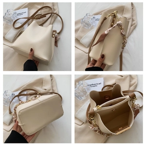 Detail view of cream bucket bag with golden hardware and interior zipper pocket