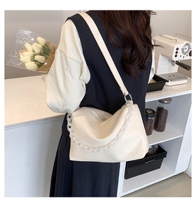 Detail of cream PU leather bag with acrylic chain and adjustable strap in cafe setting