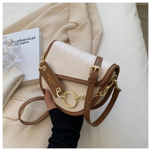 Close-up of white croc-embossed saddle bag with brown leather trim and gold hardware