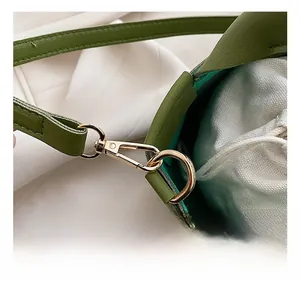 Detail of green leather handbag featuring golden metal swivel hook and drawstring liner
