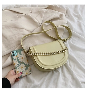 Detail of light yellow saddle bag featuring a bold gold chain and smooth PU leather